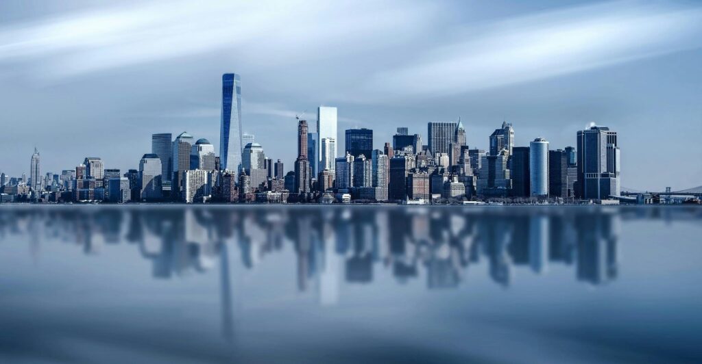 Stunning New York City skyline with modern skyscrapers reflecting on a calm river.